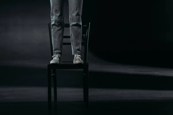 Cropped view of self-destroyer standing on chair and going to commit suicide on black background — Stock Photo
