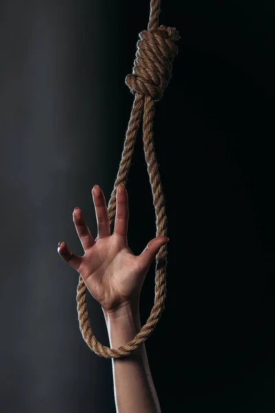 Cropped with of female hand in hanging rope noose on black background — Stock Photo