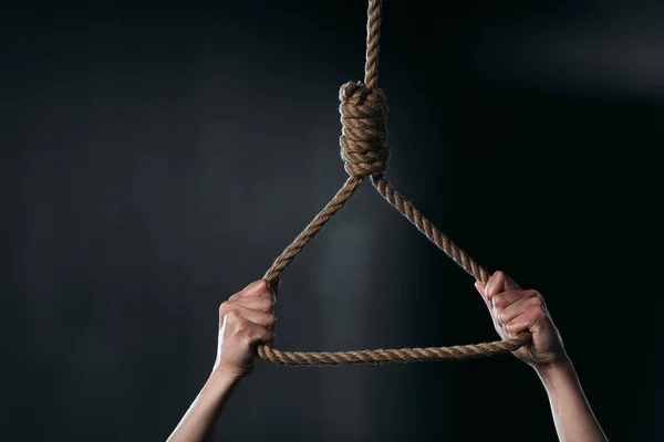 Vue recadrée d'une femme tenant une boucle de corde suspendue sur fond noir — Photo de stock