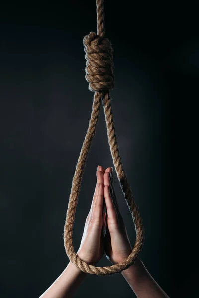 Cropped view of woman showing pray gesture near hanging rope noose isolated on black — Stock Photo