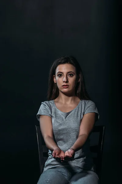 Verzagte Frau blickt in die Kamera, während sie eine Handvoll Tabletten in der Hand hält und isoliert auf schwarz Selbstmord begeht — Stockfoto
