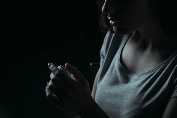 Vista recortada de la mujer que va a suicidarse y sosteniendo contenedor con pastillas aisladas en negro - foto de stock