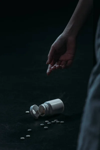 Visão cortada da mão da mulher inconsciente cometeu suicídio por overdose pílulas em fundo escuro — Fotografia de Stock