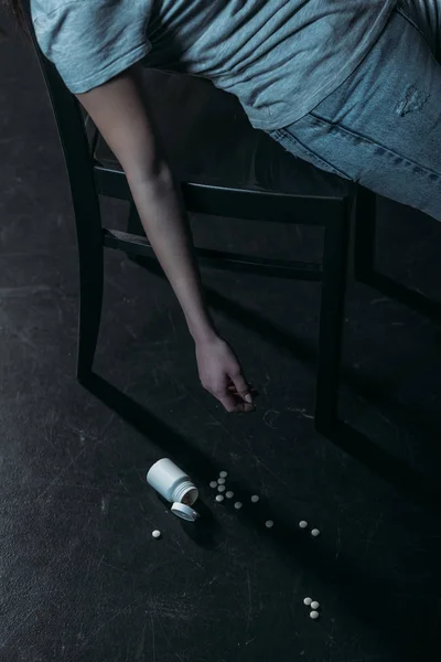 Cropped view of unconscious woman committed suicide by overdosing pills on dark background — Stock Photo
