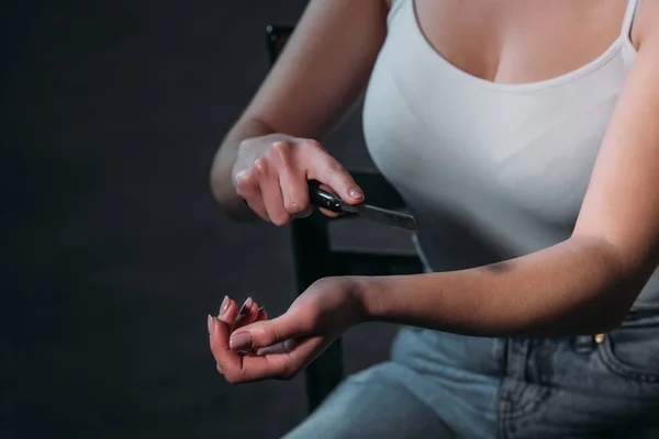 Ausgeschnittene Ansicht einer Frau, die Selbstmord begeht, indem sie Adern mit Rasiermesser auf dunklem Hintergrund durchtrennt — Stockfoto