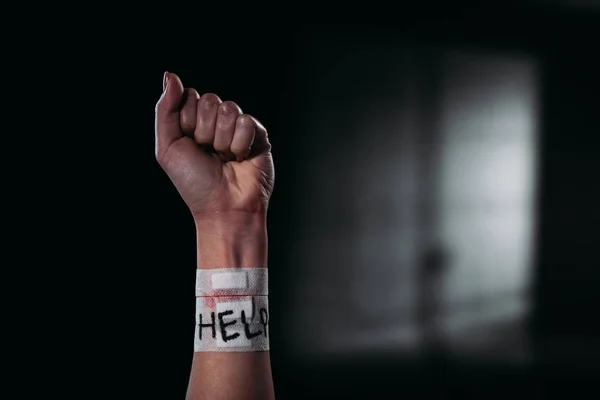 Обрезанный вид женской руки со словом помощи на медицинских участках покрывающих разрез вен на черном фоне с освещением — стоковое фото