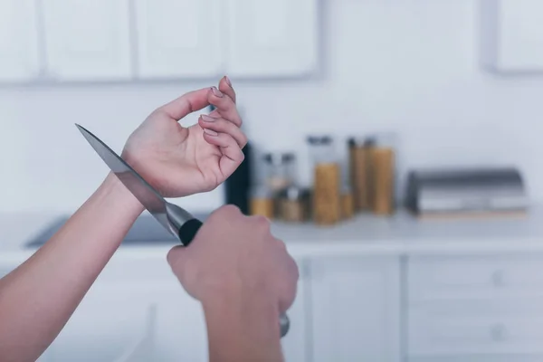 Visão parcial da mulher deprimida cometendo suicídio cortando veias com faca na cozinha — Fotografia de Stock