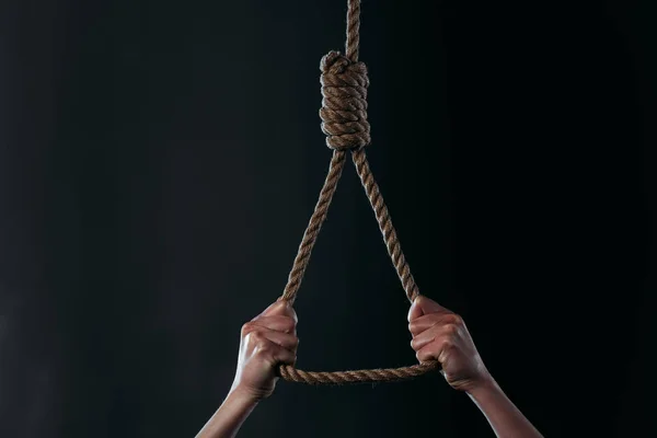Vista recortada de la mujer desesperada que va a suicidarse mientras sostiene la soga colgante aislada en negro - foto de stock