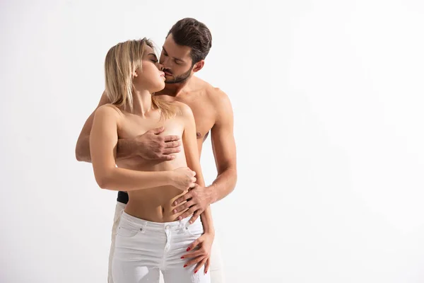 Пристрасний чоловік цілує і покриває груди своєї оголеної подруги, ізольовані на білому — стокове фото