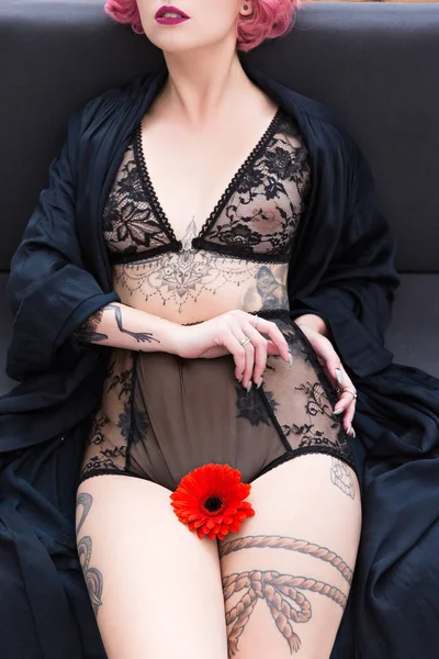 Hermosa joven en ropa interior negra con tatuajes y flor roja - foto de stock
