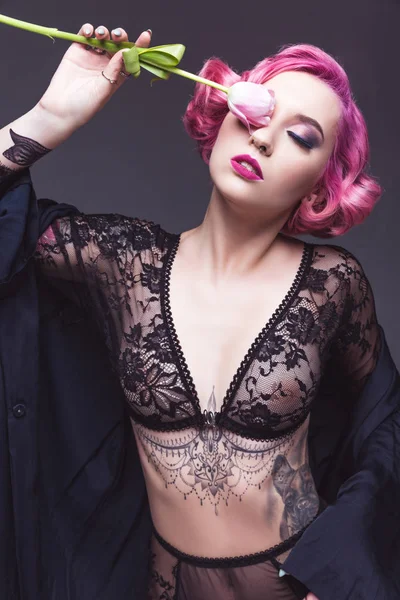 Sexy tatuato pin up ragazza in lingerie trasparente con fiore davanti di sfondo grigio — Foto stock