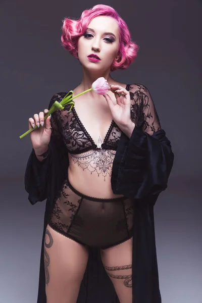Sedutor tatuado pin up menina em lingerie transparente com flor na frente de fundo cinza — Fotografia de Stock