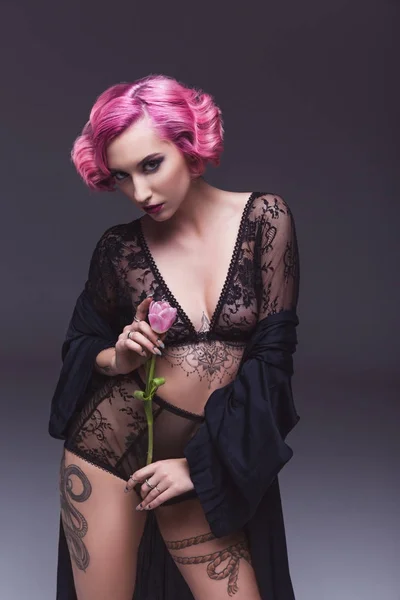 Seducente tatuato ragazza in lingerie tenendo fiore davanti di sfondo grigio — Foto stock