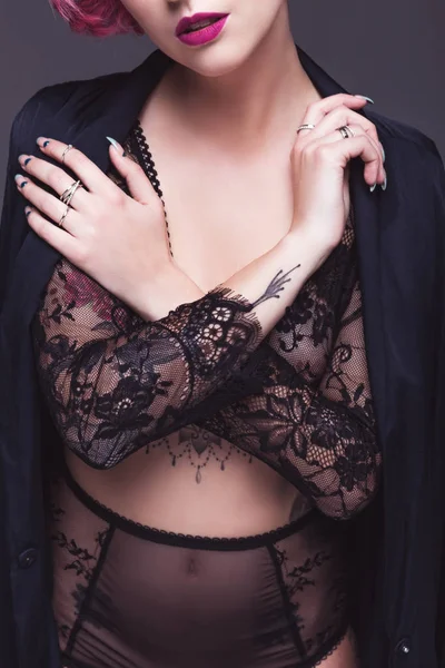 Обрезанное изображение татуированной девушки в прозрачном нижнем белье на сером фоне — стоковое фото