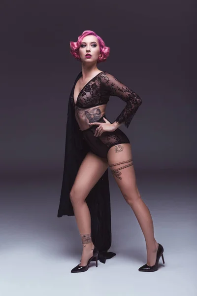 Sedutor tatuado pin up menina em lingerie transparente na frente de fundo cinza — Fotografia de Stock