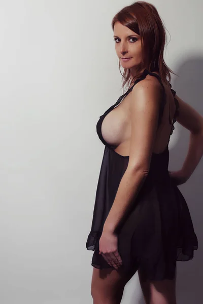 Junges schönes und sexy weibliches Modell im schwarzen Nachthemd. — Stockfoto